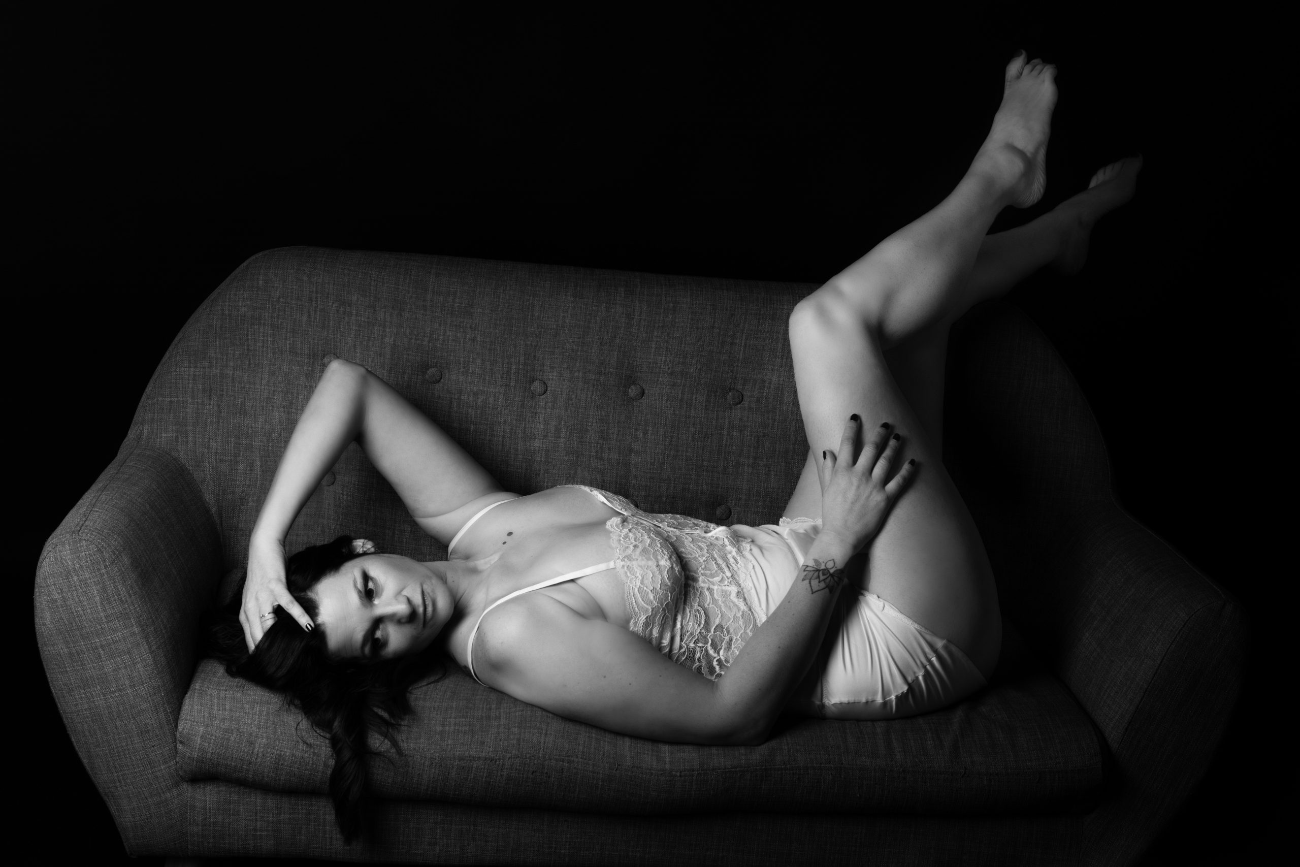 séance photo boudoir lyon Femme allongée sur un canapé lors d'une séance photo boudoir en noir et blanc à Lyon.
